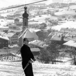 Skifahrer am Hausberg in Reit im Winkl und Pfarrkirche im Hintergrund